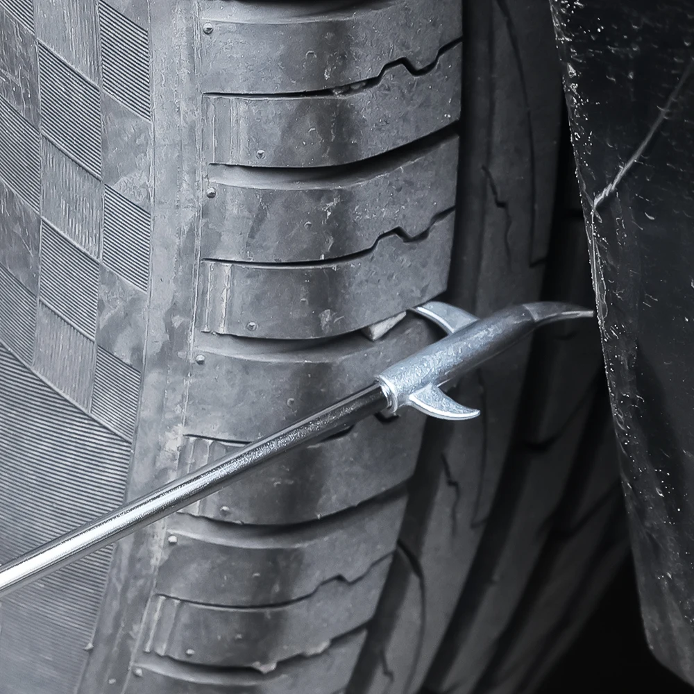 Removing a stone from a car tire tread with a metal hook